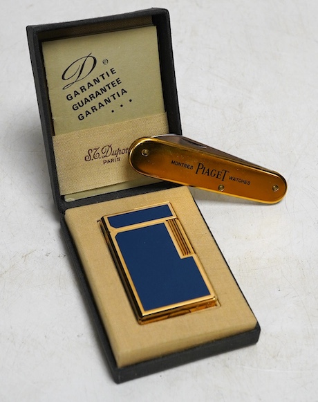 A Dupont gilt metal and blue enamel cigarette lighter with Japanese characters to the side, boxed with papers and a Piaget Montres Watches folding knife, cased. Condition - good